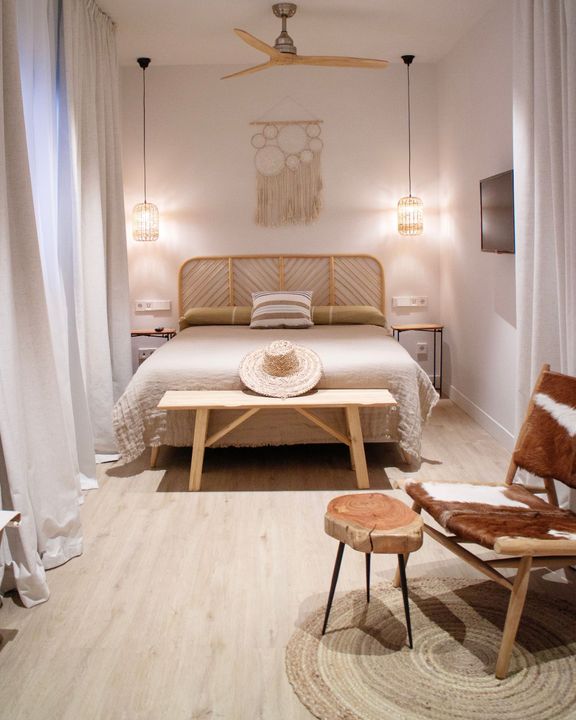 A bedroom with a bed , bench , chair and ceiling fan.