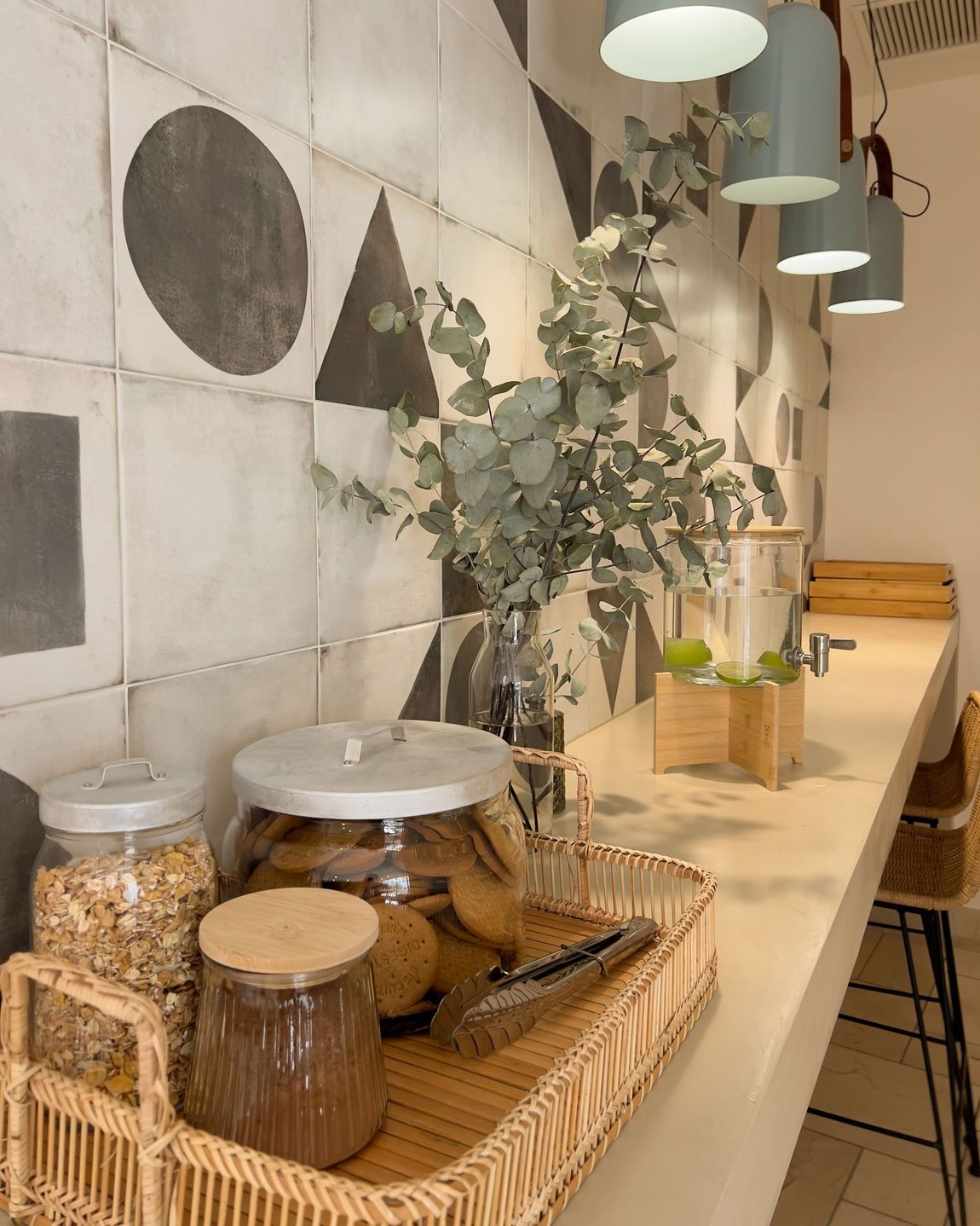 A kitchen counter with a wicker tray filled with jars of food.