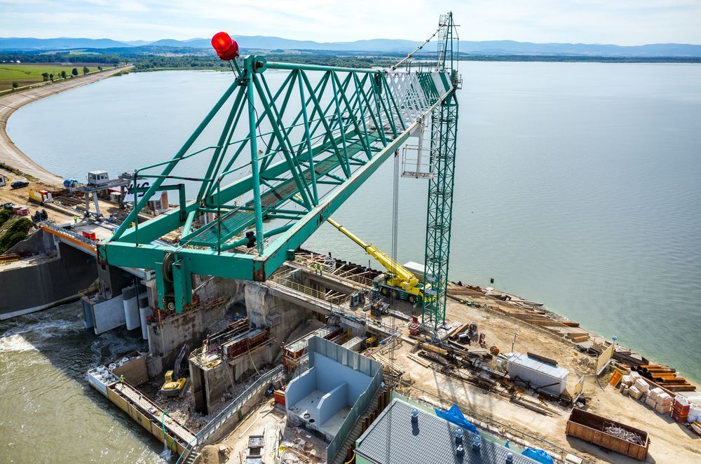 A Large Green Construction Crane is Positioned Over a Dam — BC Earthmoving and Tipper Hire in Cooroy, QLD