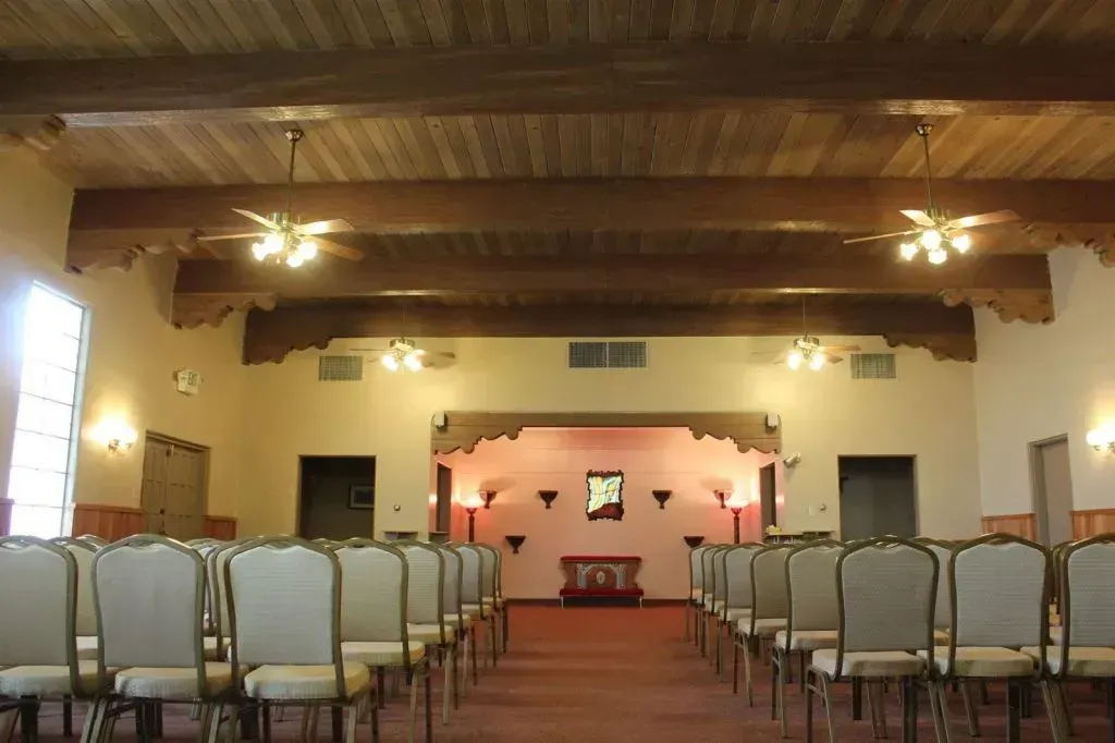 Modern building with a dark roof and covered entrance, in a parking lot at dusk.