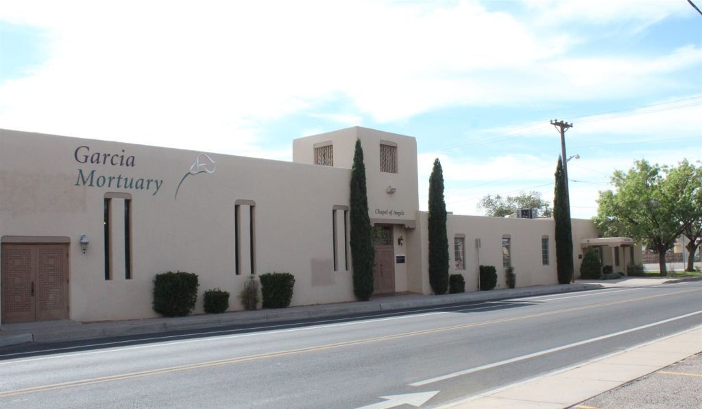 Rendering of a memorial with a central cross and surrounding structures, trees, and sky.