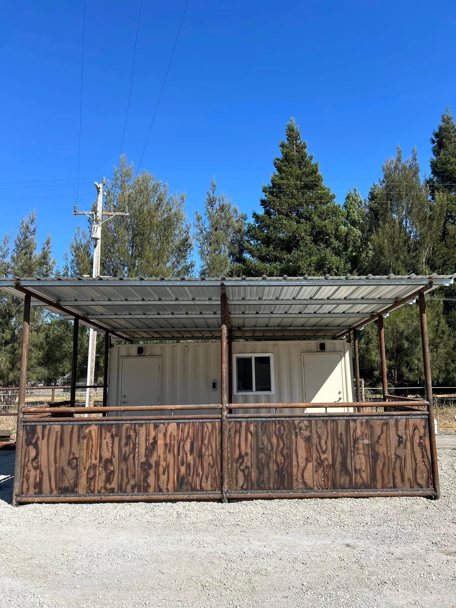 Covered outdoor structure with brown wooden fencing and a metal roof. A window is visible.