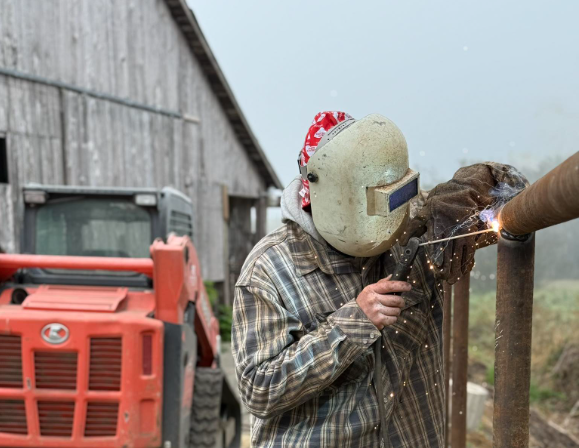 Two people working near a large container on a construction site outdoors on a sunny day.