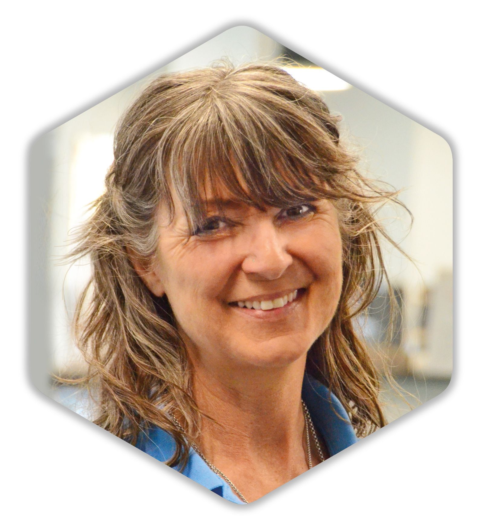 Eine Frau in einem blauen Hemd lächelt in die Kamera