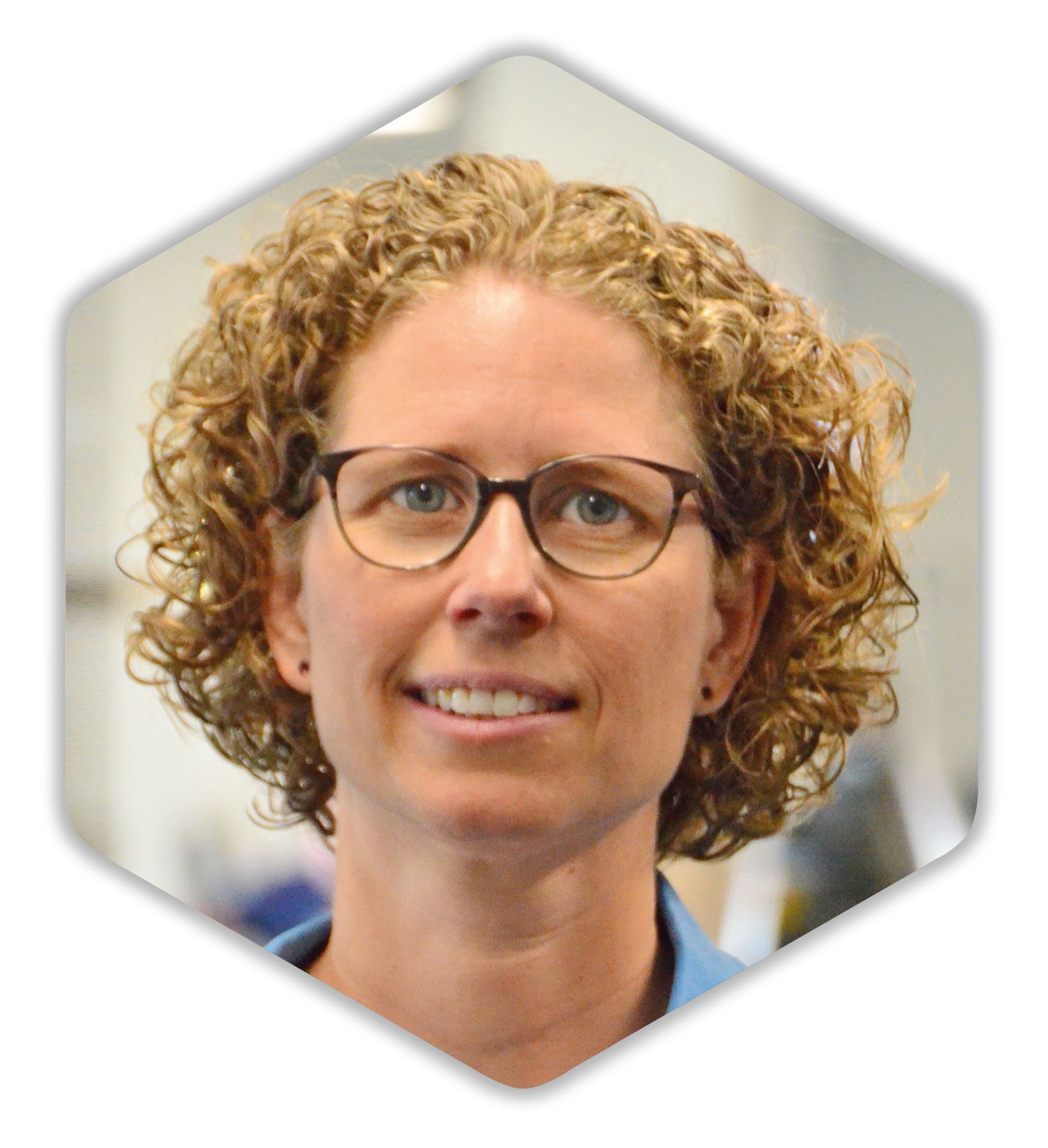 Eine Frau mit lockigem Haar, Brille und blauem Hemd