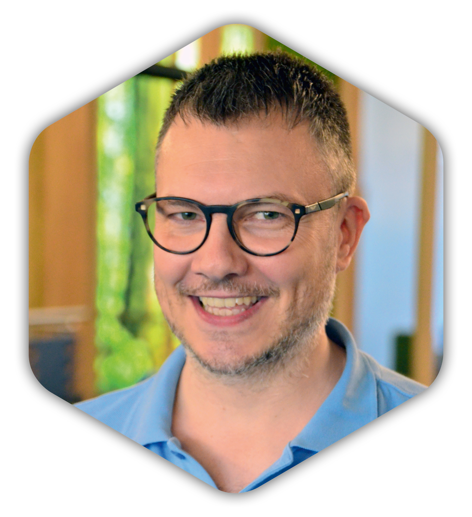 Ein Mann mit Brille und blauem Hemd lächelt.