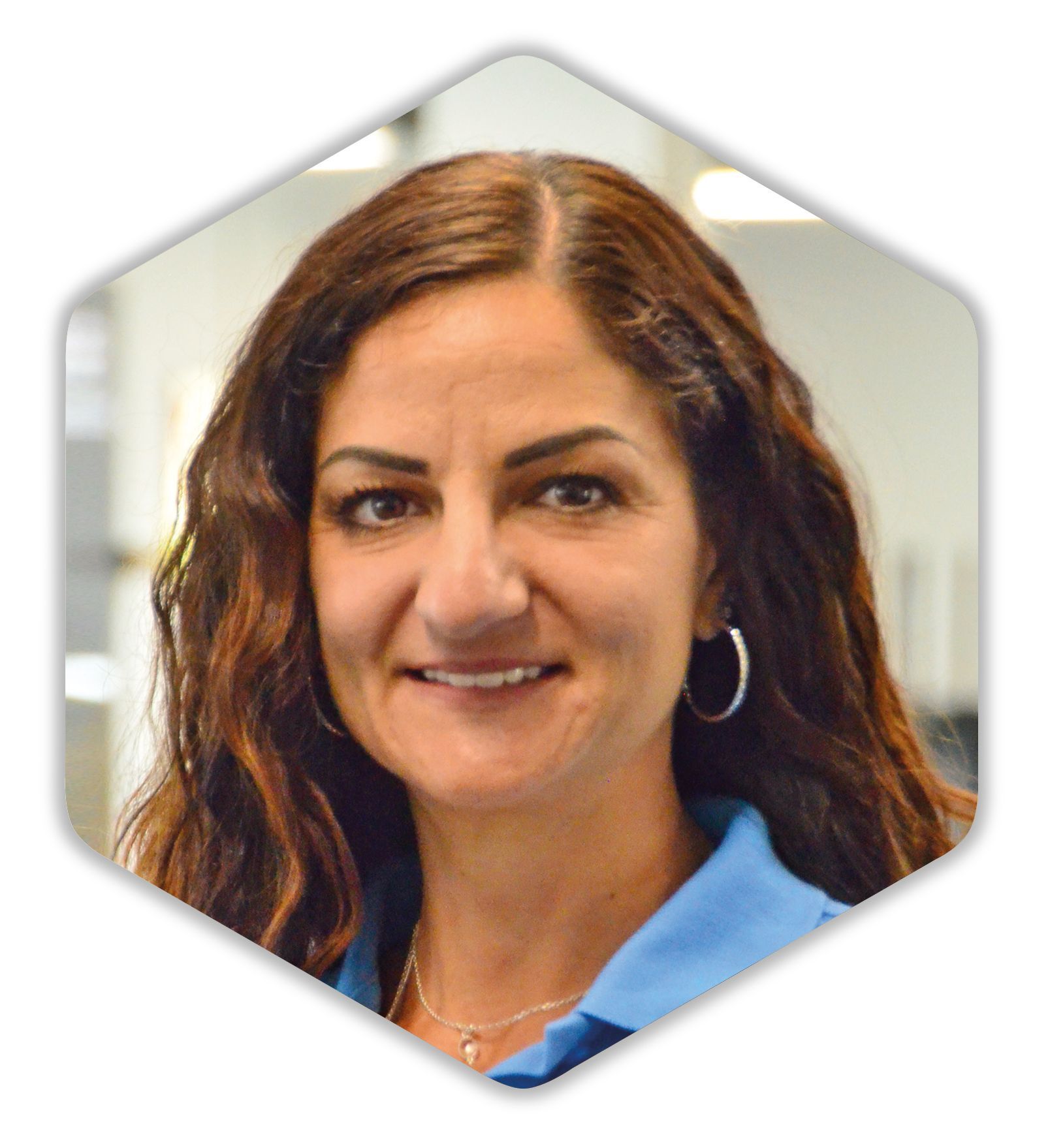 Eine Frau in blauem Hemd und Creolen lächelt in die Kamera