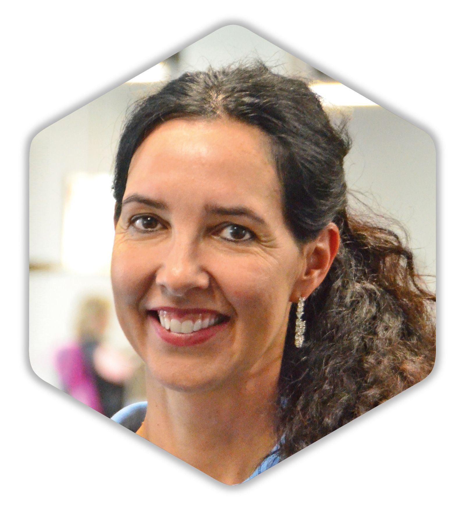 Eine Frau mit lockigem Haar lächelt und trägt Ohrringe