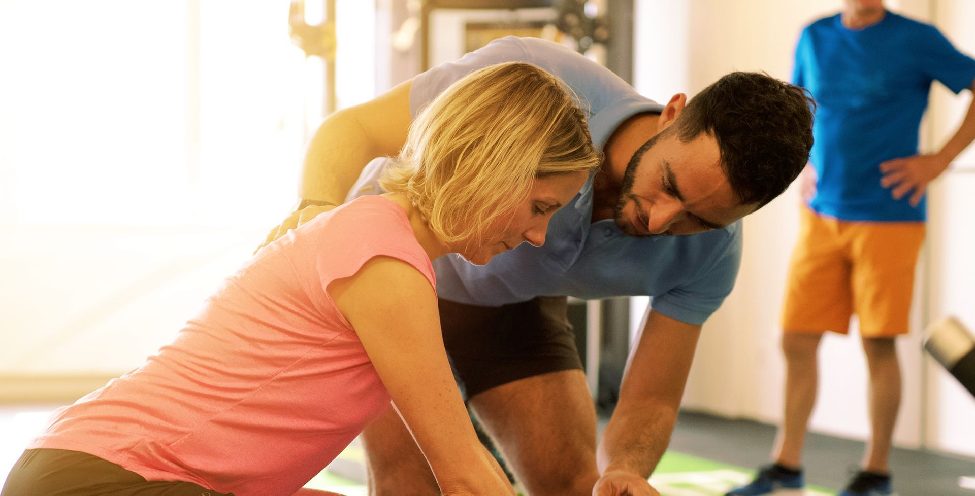 Ein Physiotherapeut hilft einer Frau beim Üben im Fitnessstudio