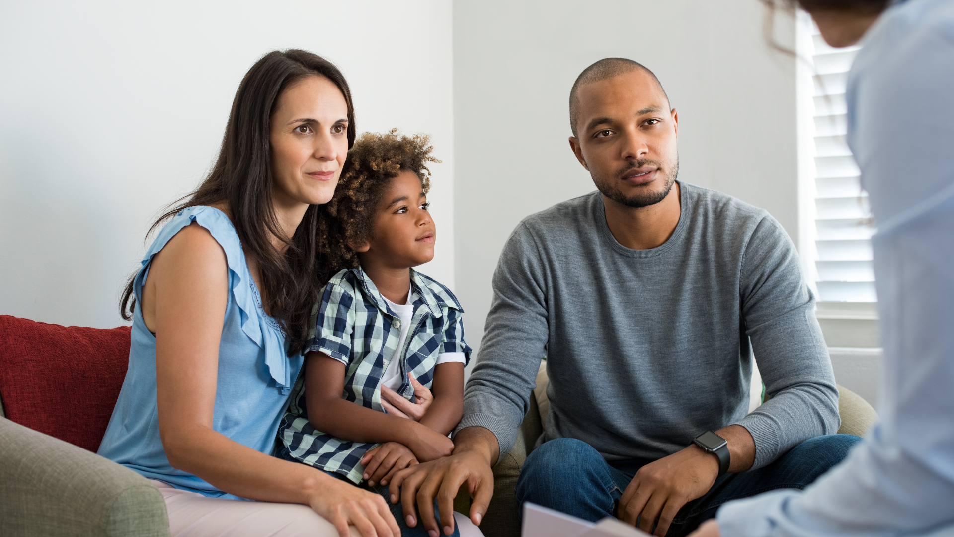 Family of three seated, looking at a person off-camera.