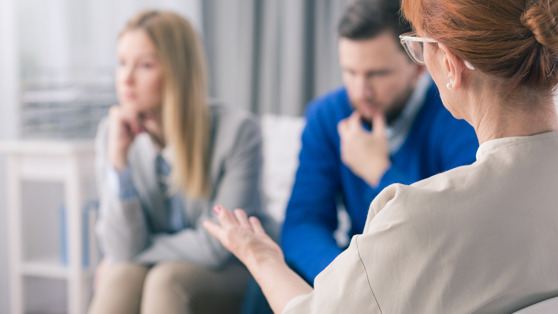Couple in therapy with therapist; couple looks distressed while therapist gestures with hand.