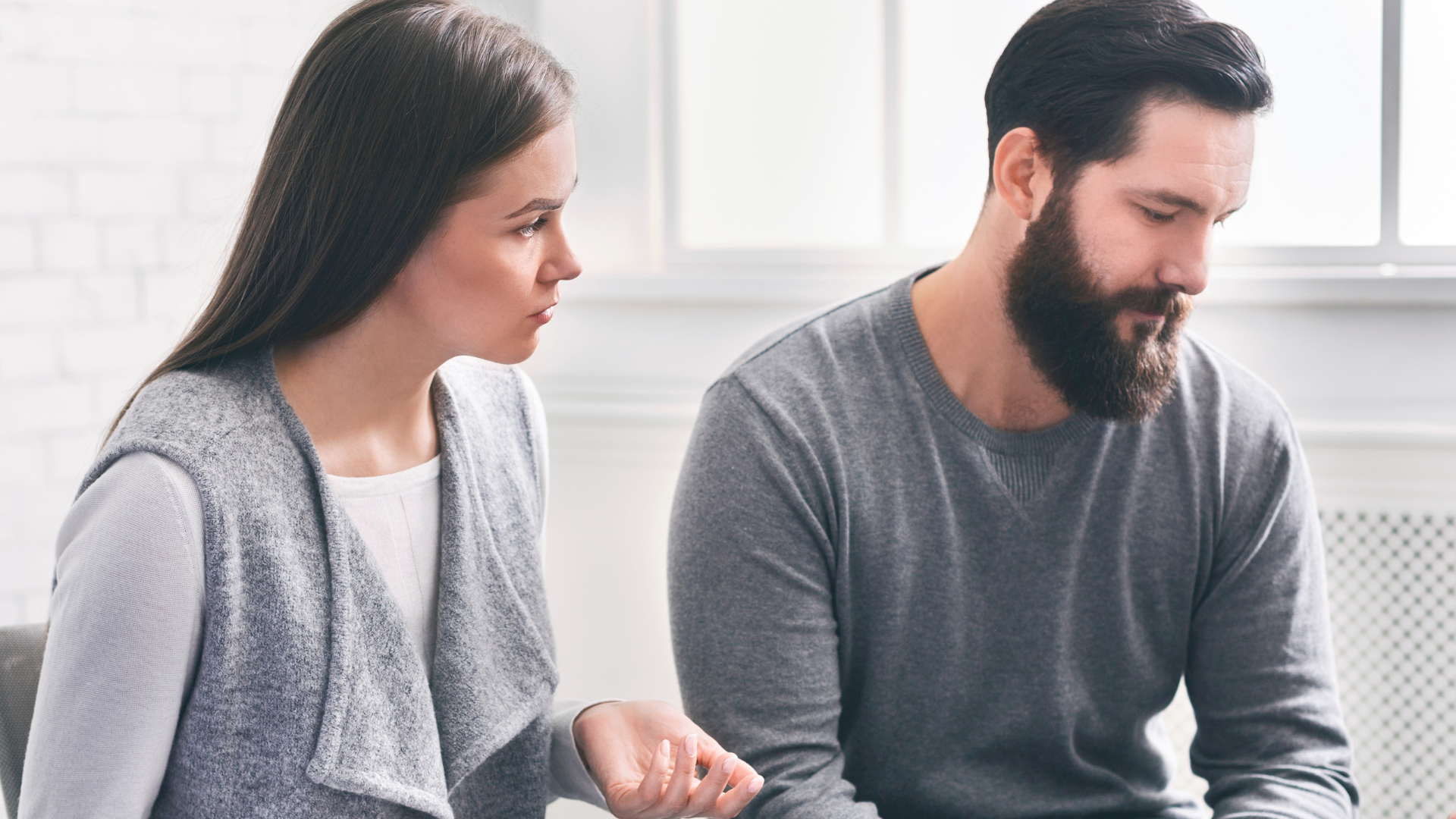 Woman talking to a man in a counseling setting. The man looks down, saddened.