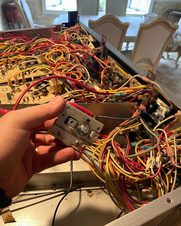 A person is holding a piece of metal in front of a bunch of wires.