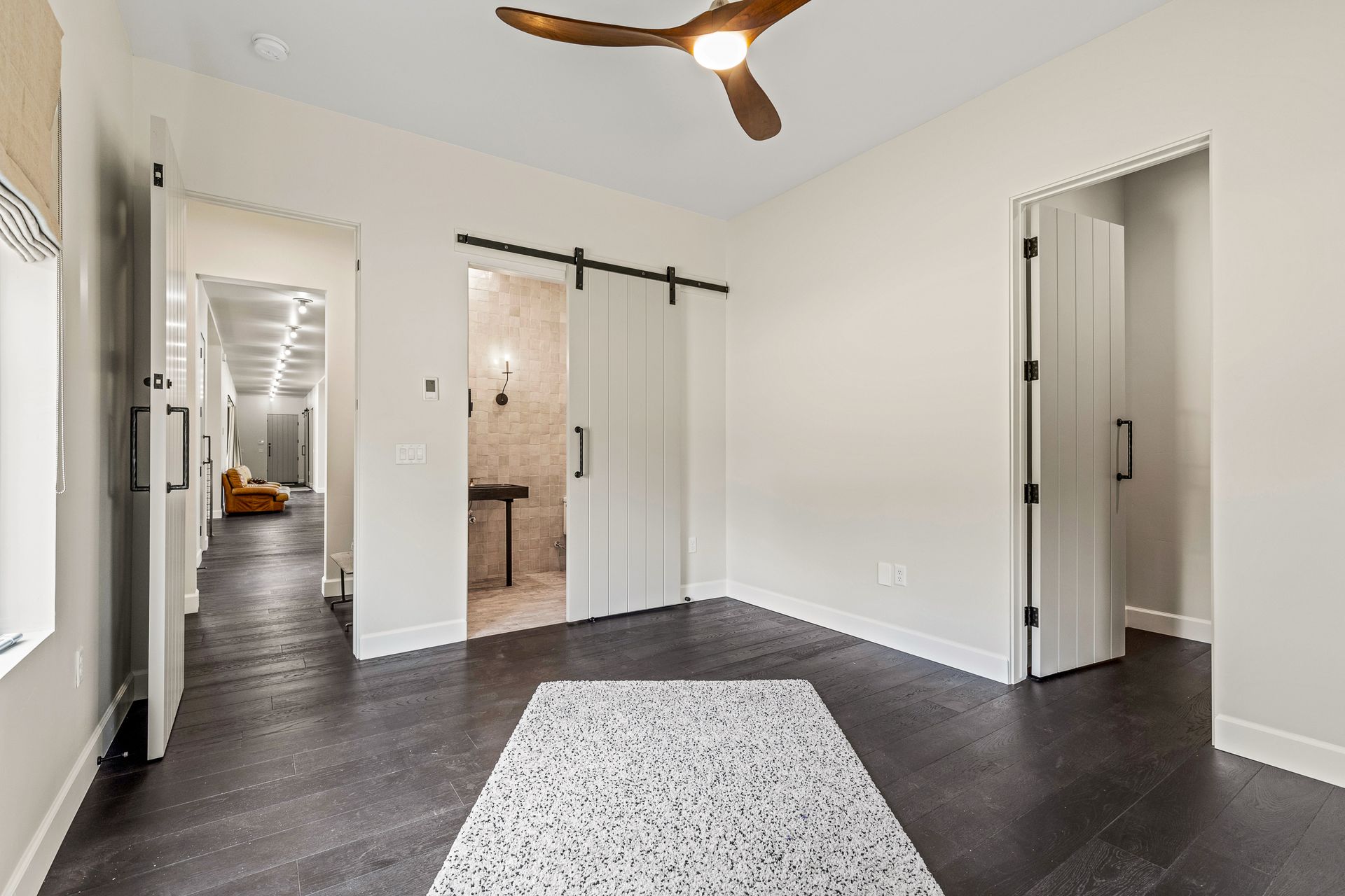 A bedroom with a ceiling fan and sliding barn doors