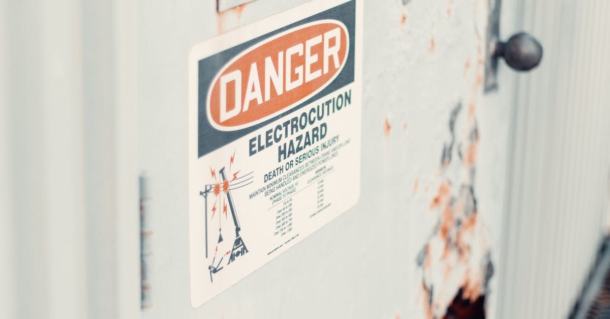 A white sticker on a door with a DANGER header, Electrocution Hazard text, and a diagram of a crane near power lines.