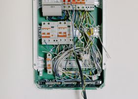 Open residential electrical panel with circuit breakers being inspected by an electrician