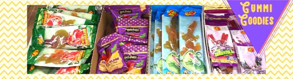 Assorted colorful gummy candy packages arranged in rows on a white background, with Yummi Goodies logo