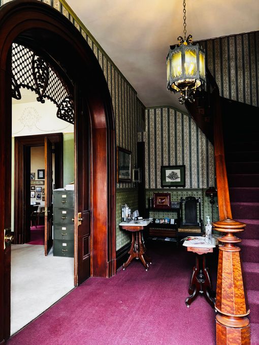 A hallway with a staircase and a purple carpet