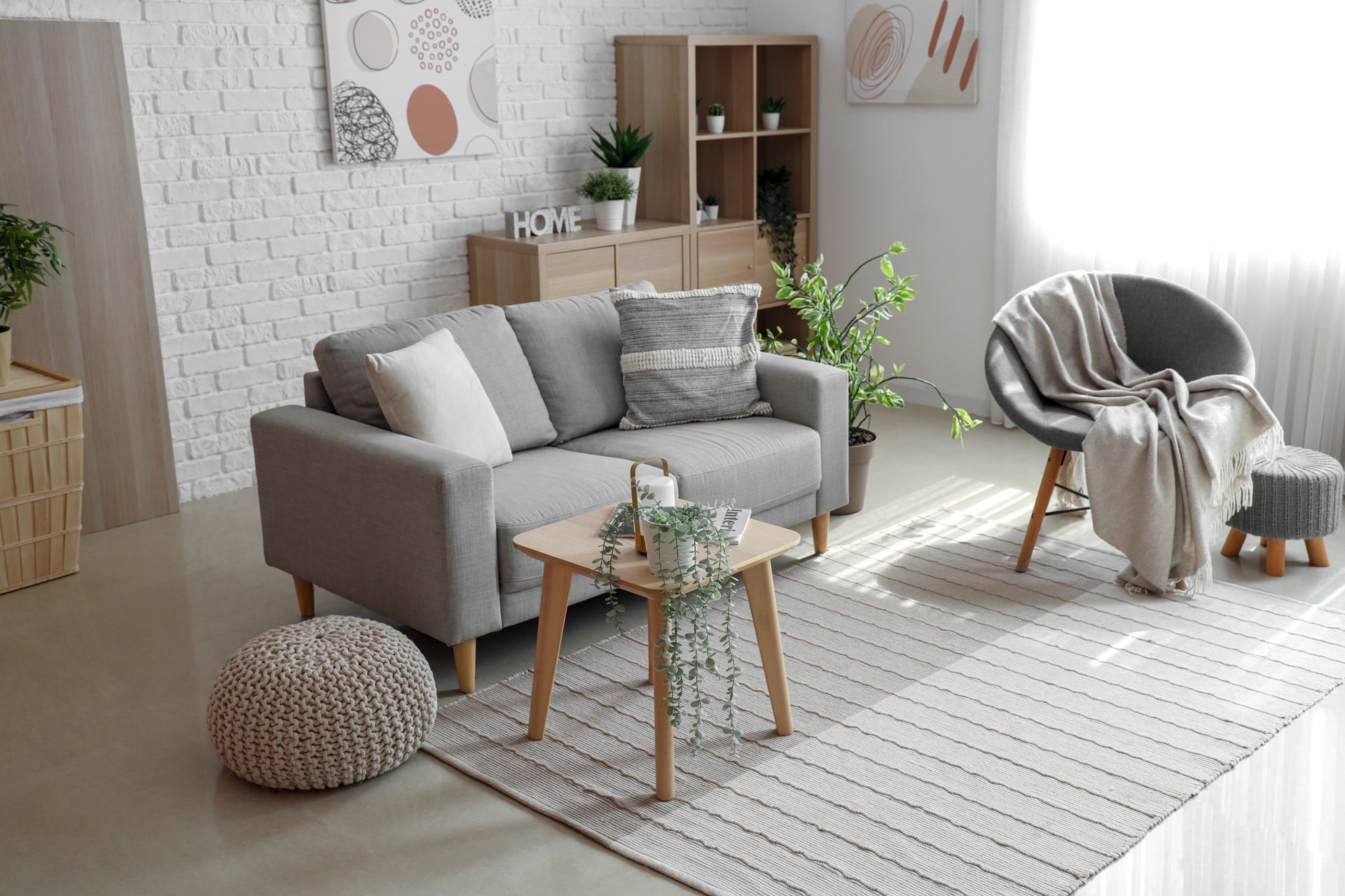 Accogliente soggiorno con divano grigio, tappeto a righe, poltrona rotonda e dettagli decorativi in legno chiaro.