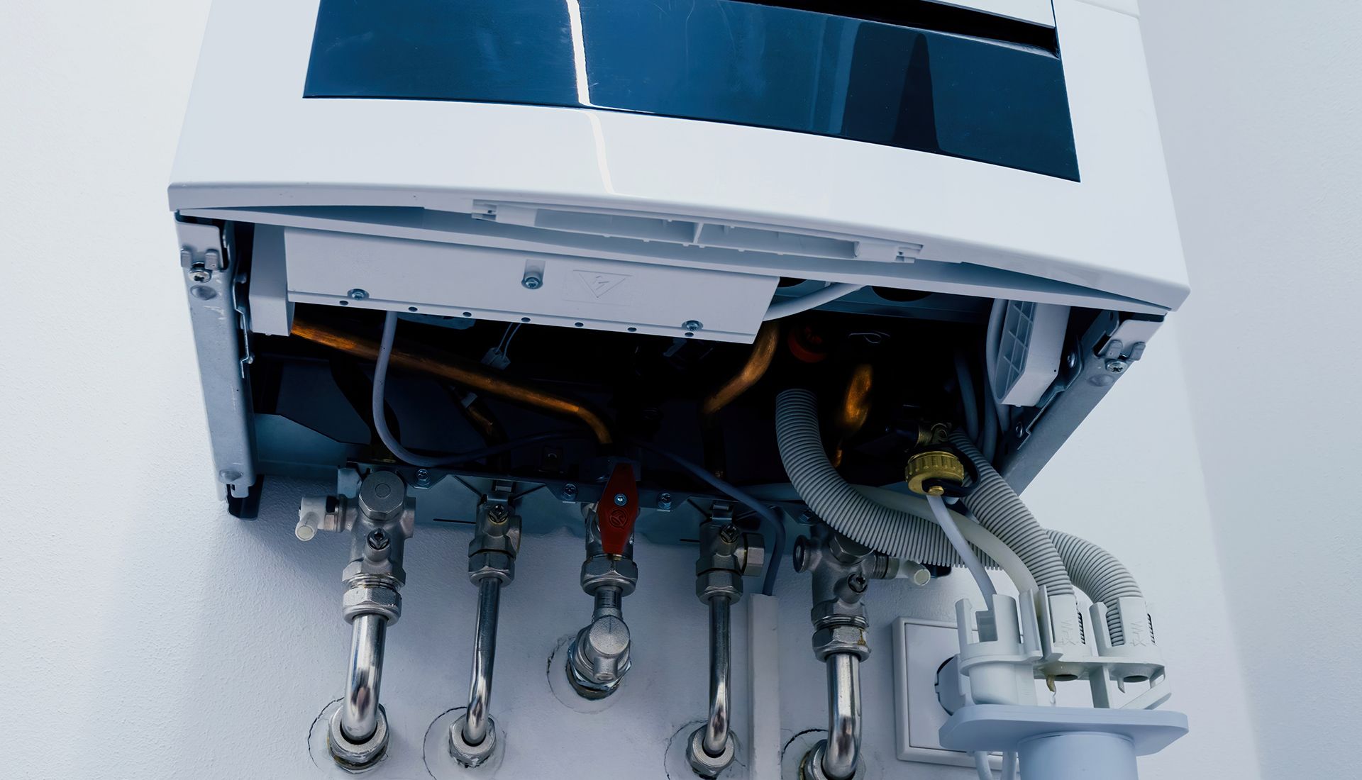 White wall-mounted gas boiler with exposed internal components and plumbing connections.