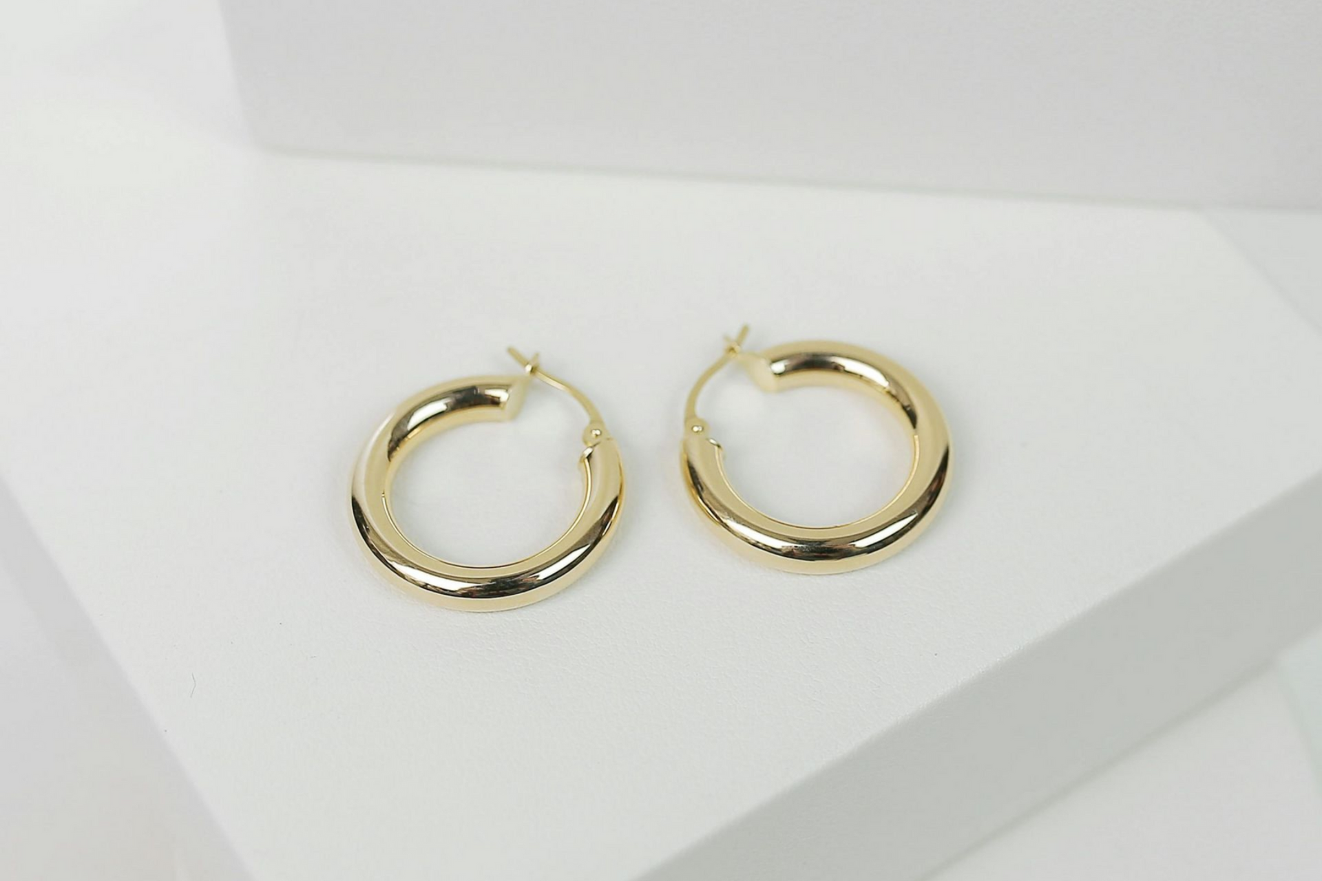 Pair of small gold hoop earrings on a white surface