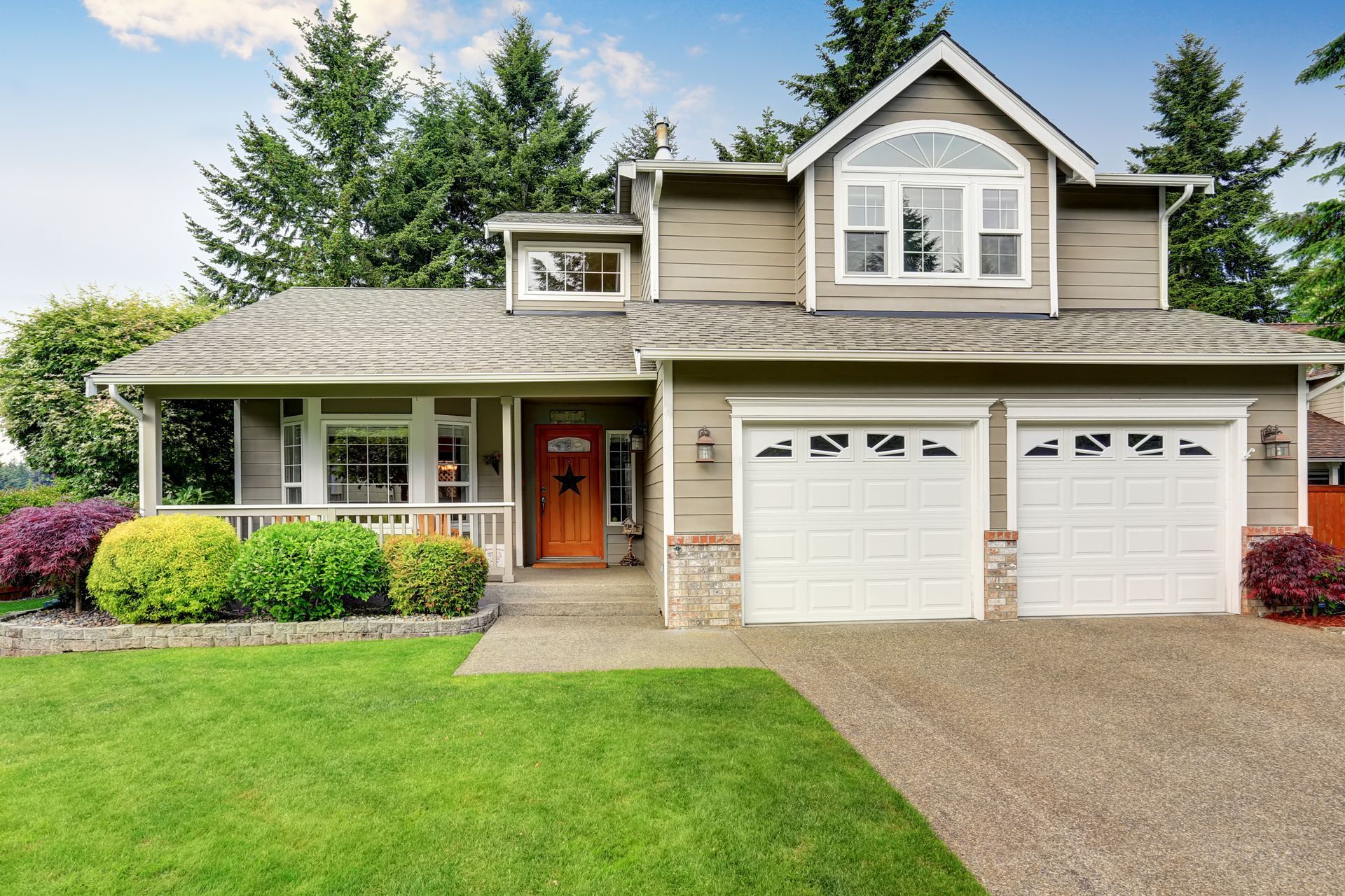 Two-story house with green lawn, driveway, and attached two-car garage. Beige siding, white trim, and a brown door.