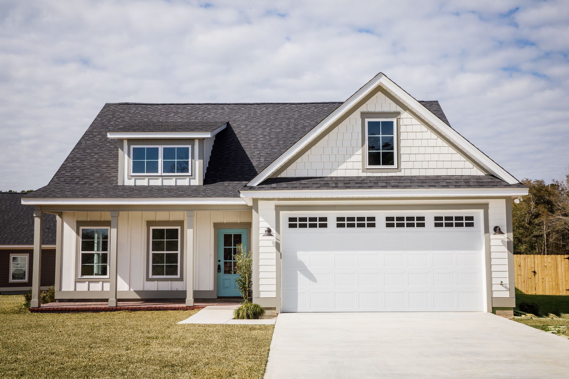 White house with a gray roof, blue door, and a two-car garage.