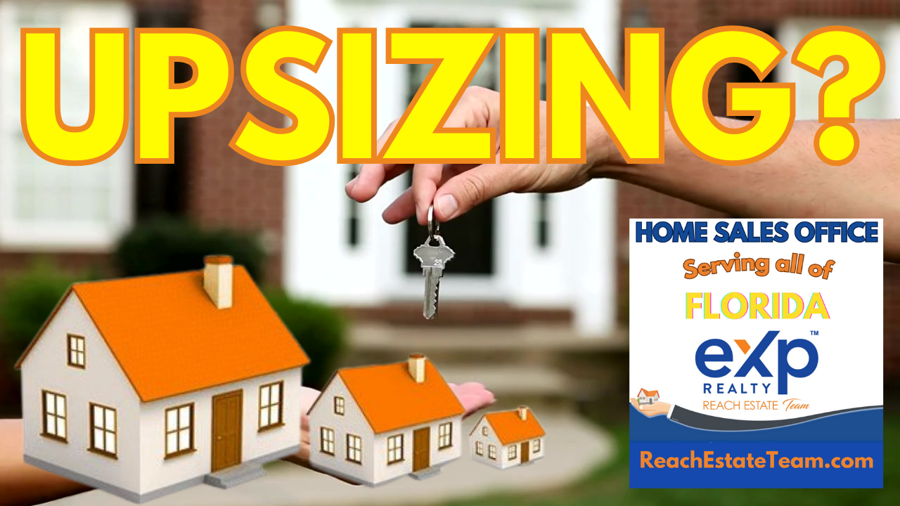 A person is holding a key in front of a model house.