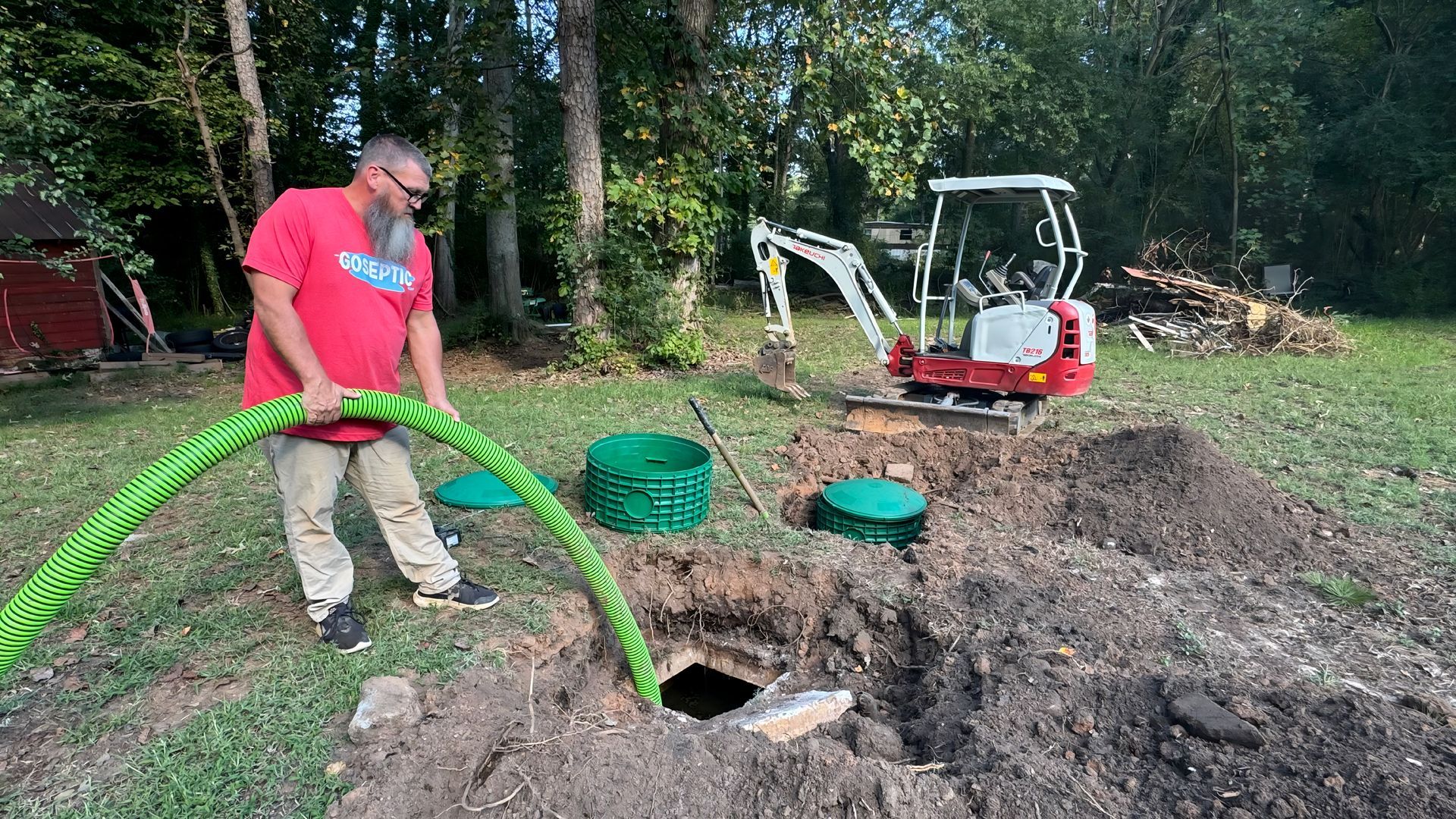 A man is using a plunger to unblock a sink in a kitchen.