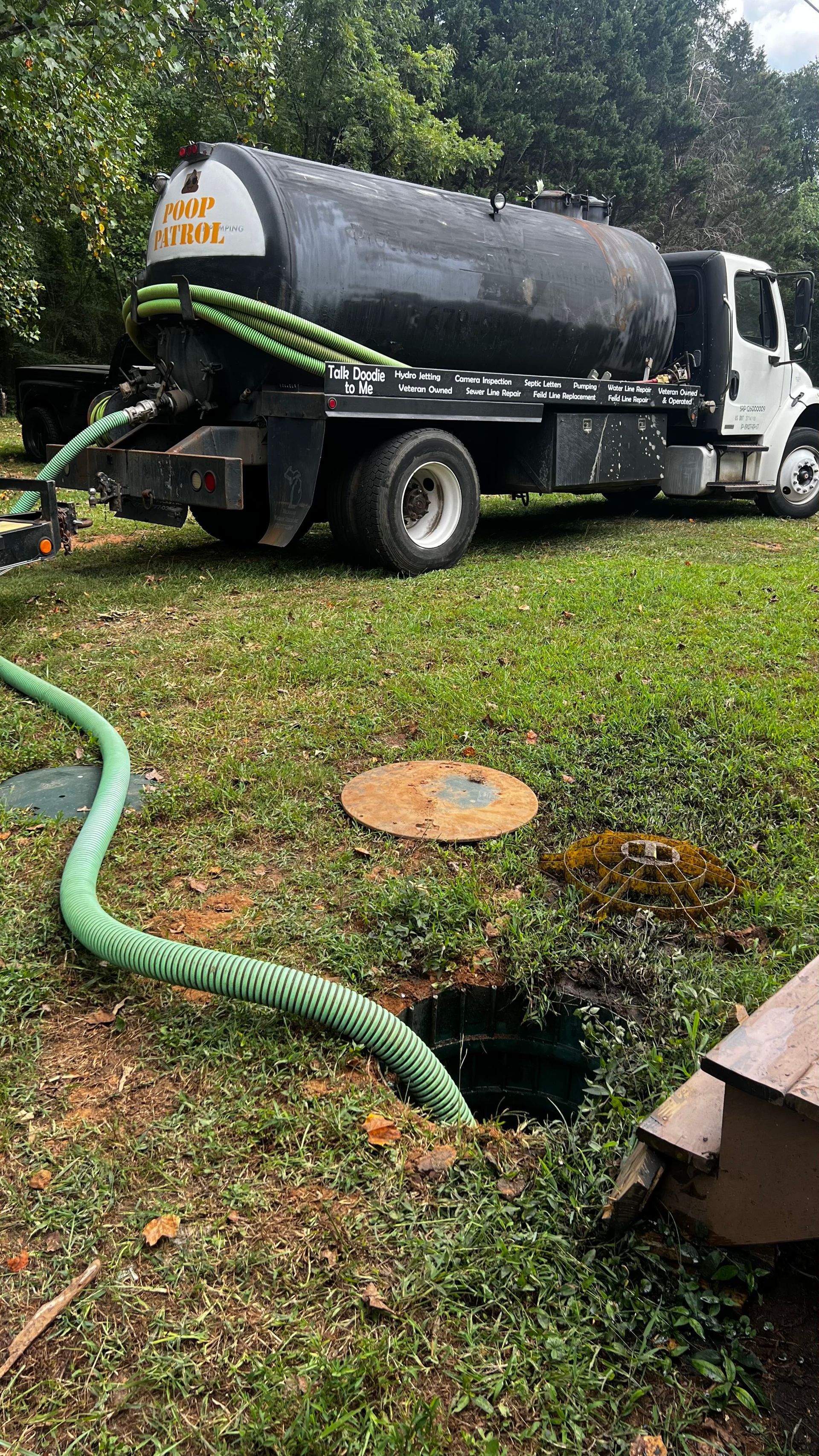 A septic tank truck is pumping water into a septic tank.