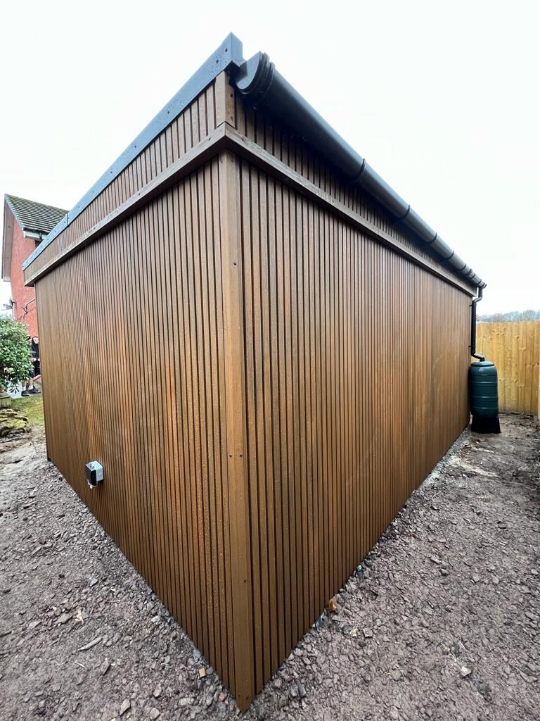 a wooden garden building with a green water tank next to it