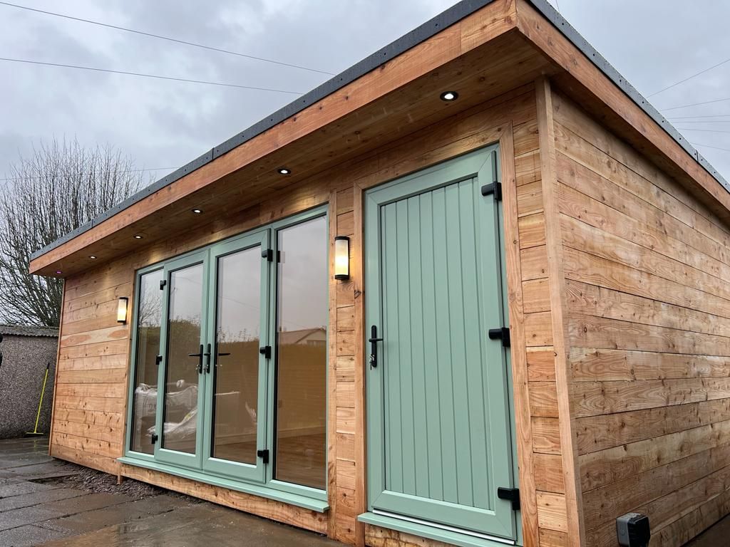 a garden room building with green doors and windows