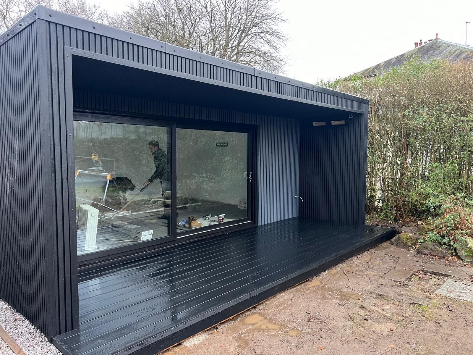 Modern 6m x 5m garden gym room in Bearsden with 1.5m roof overhang to sides, 2m deep composite decking, exterior sockets, and 3kW infrared outdoor heater.