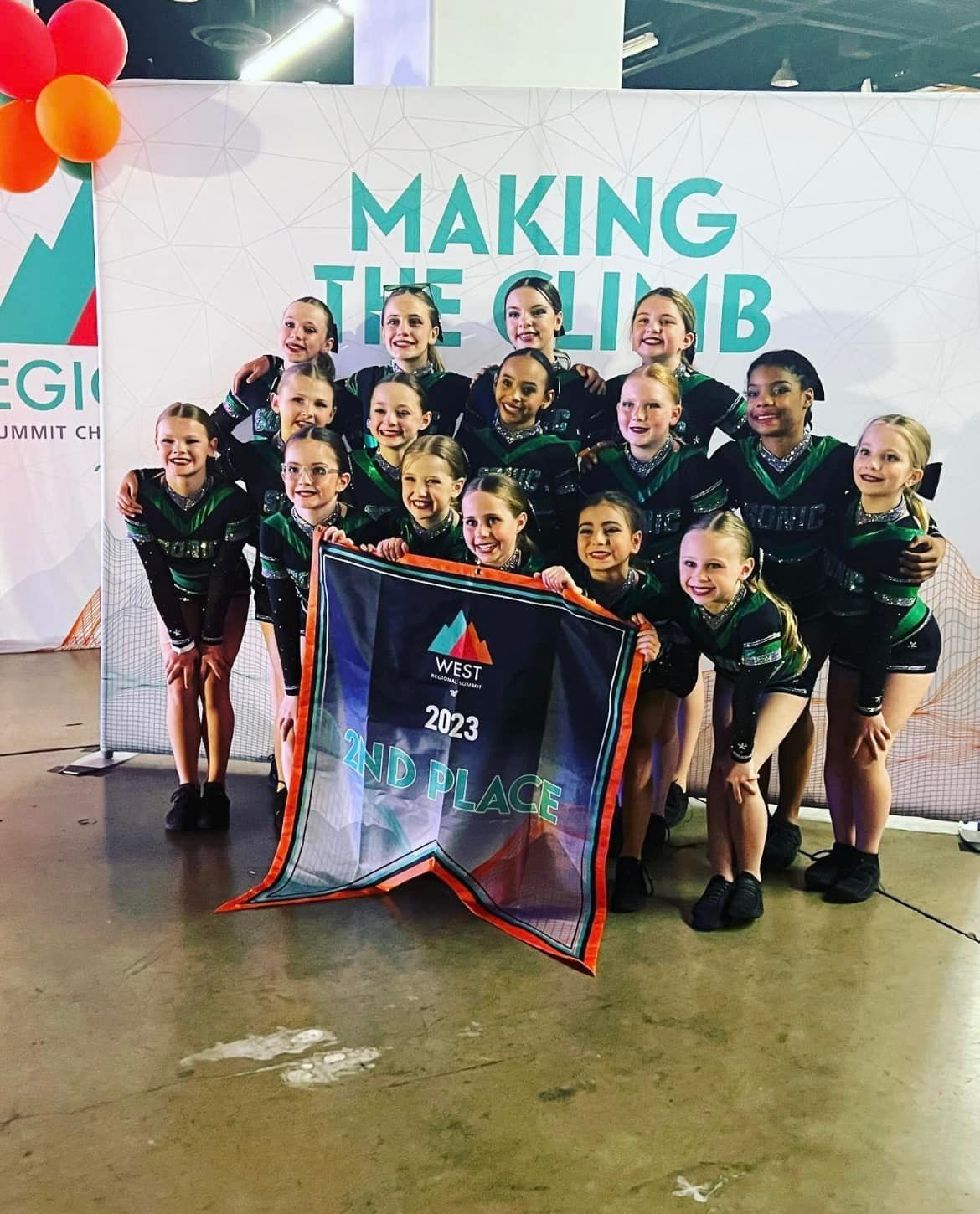 Cheerleading team holding banner, celebrating; green and black uniforms, 