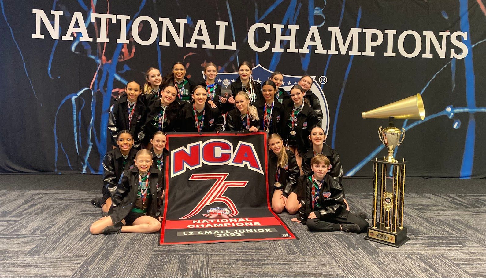 Dance team poses with trophy and banner that says National Champions.