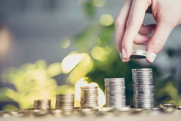 A woman's hand puts money on a pile of money.A woman's hand puts money on a pile of money.