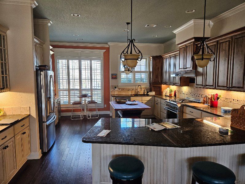 Kitchen with dark granite counters, dark wood cabinets, and a center island with bar stools.