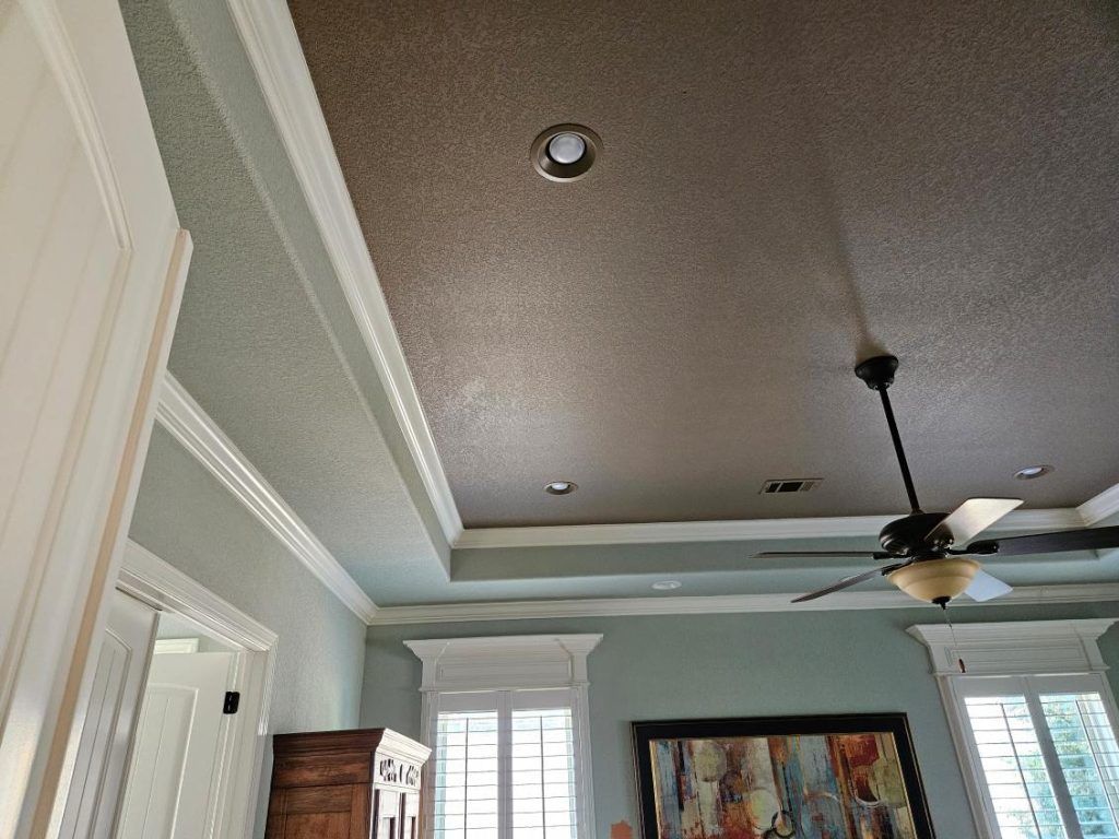 A room with a tray ceiling, fan, and recessed lighting.  Walls are green and white.