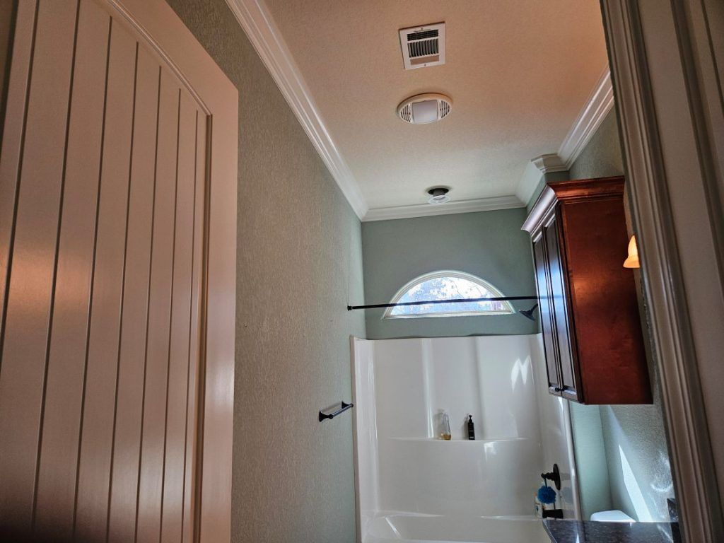 Bathroom interior with shower, cabinet, and light fixtures.