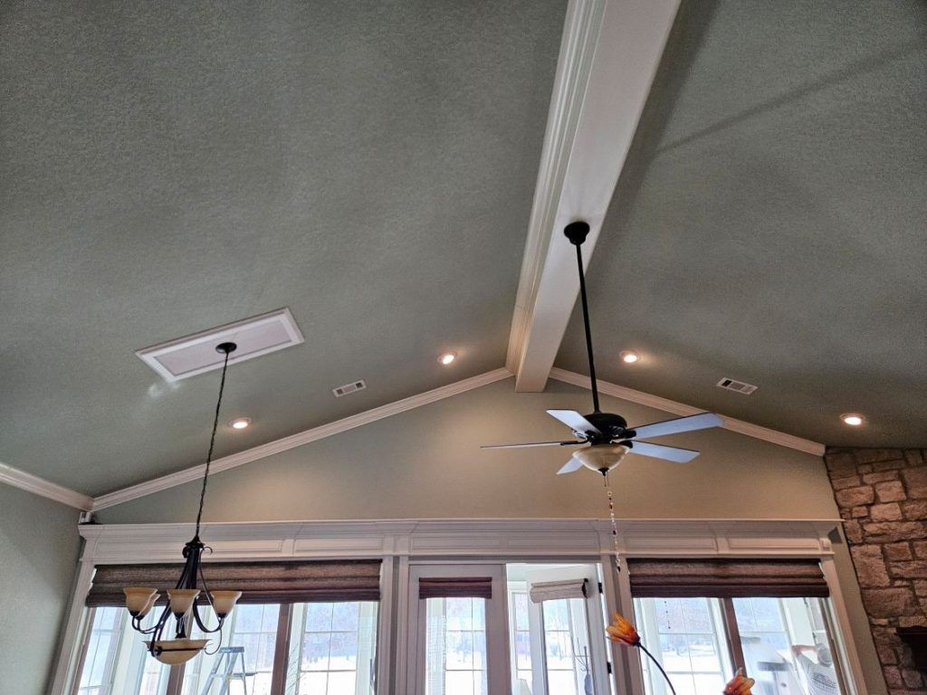 High-ceilinged room with fan, lights, and windows. The ceiling is green and white.