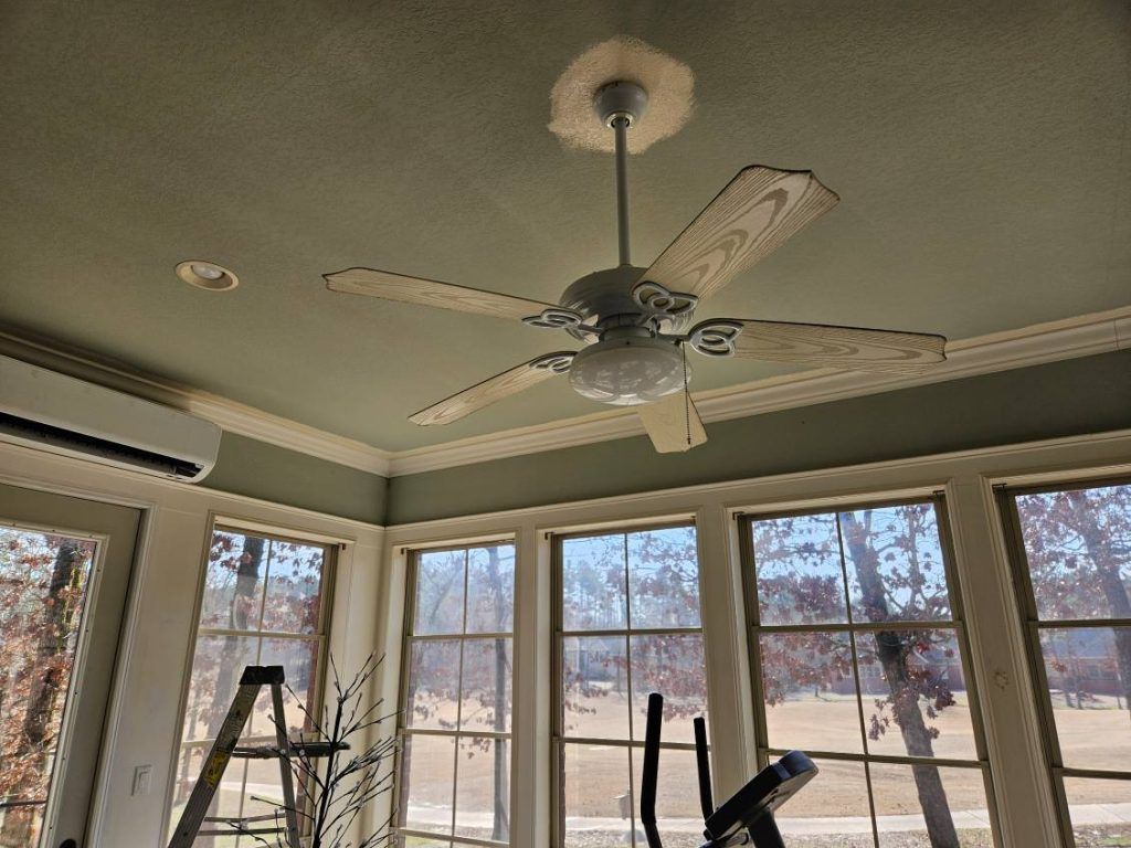 Ceiling fan in a sunroom with windows, green ceiling, and white trim.