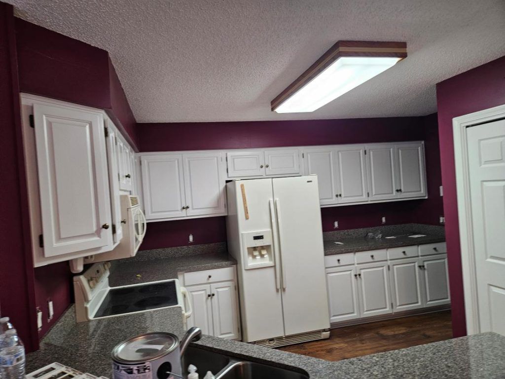 Kitchen with white cabinets and burgundy walls; stainless steel appliances.