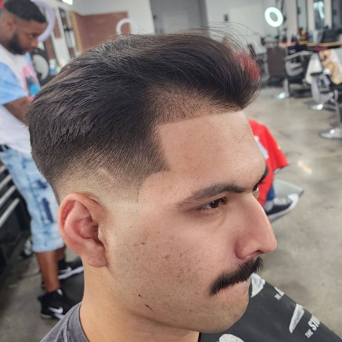 a man with a mustache is getting his hair cut at a barber shop .