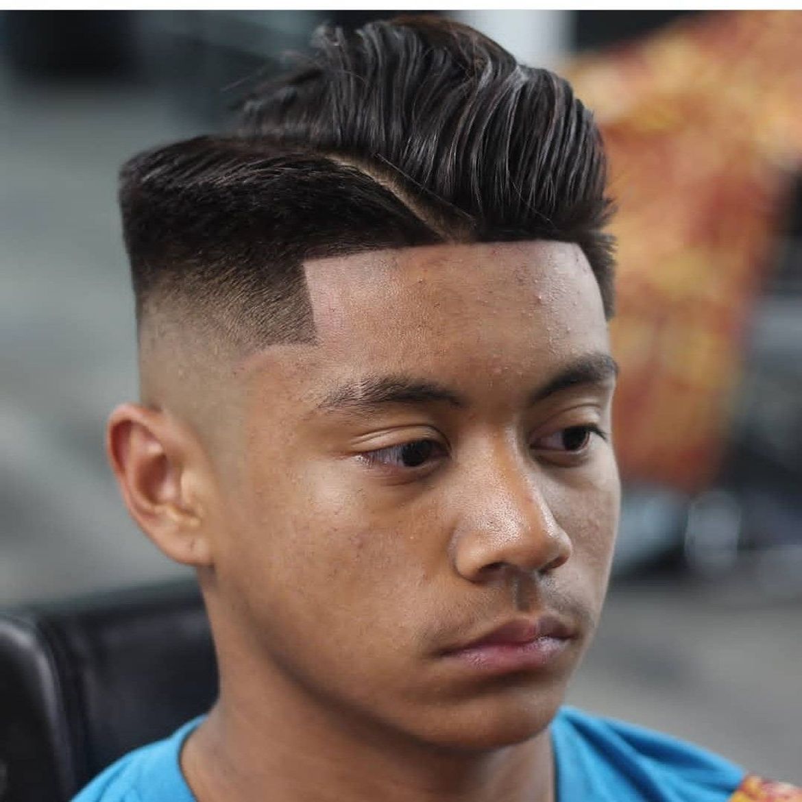 a young man with a very short haircut is wearing a blue shirt
