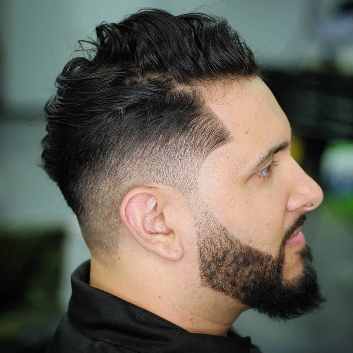 a man with a beard is getting his hair cut at a barber shop .