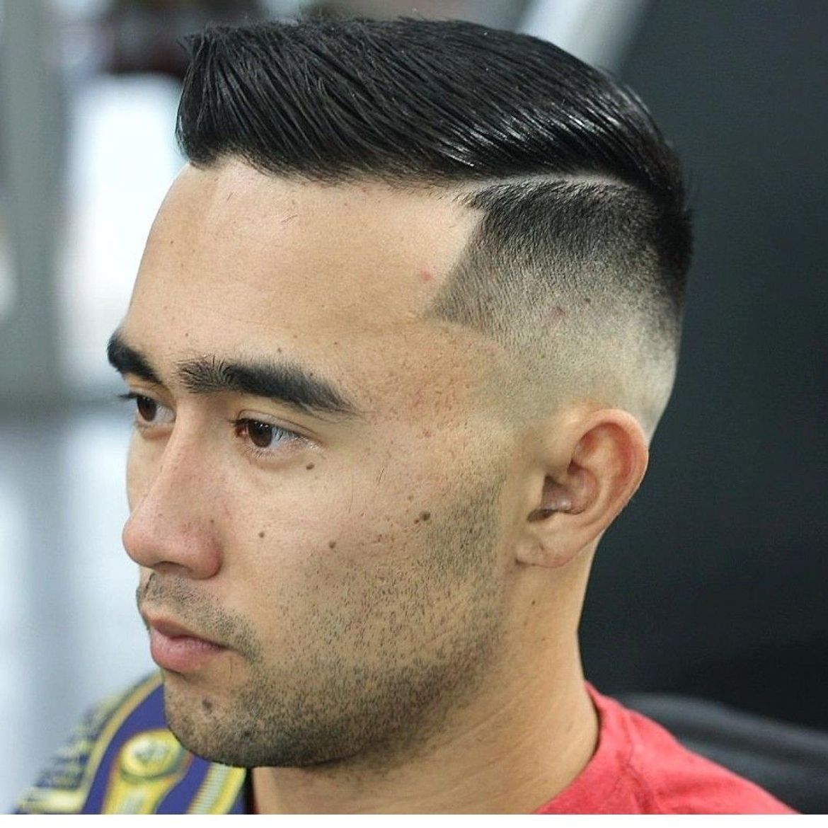 a man with a shaved head is wearing a red shirt