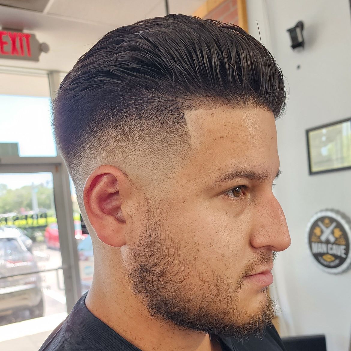 a man with a beard is getting his hair cut at a barber shop .