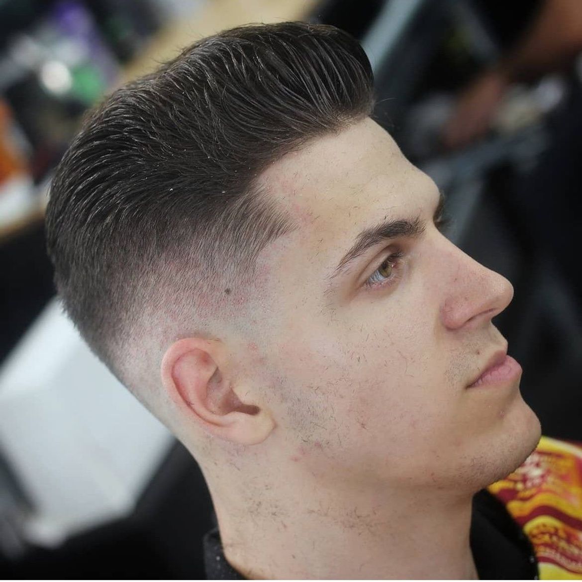 a young man is getting his hair cut at a barber shop .