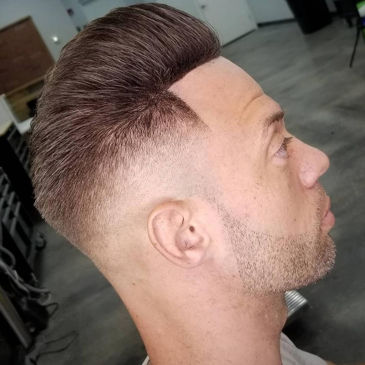 a man with a beard is getting his hair cut at a barber shop .