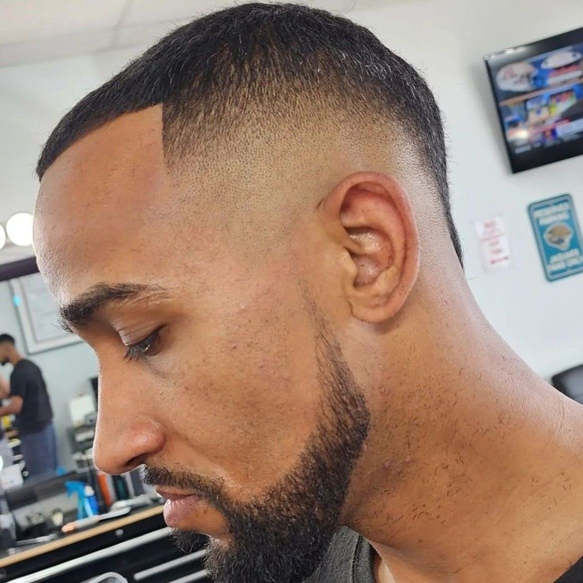 a man with a beard is getting his hair cut at a barber shop .